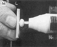 Glue a found stick on the tenon of the knob. To part the knob from the lathe, use a long pointed skew or parting tool.